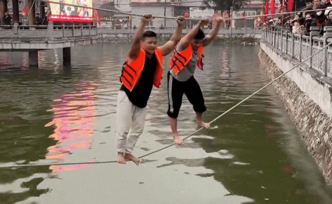 Nín thở từng giây xem gymer gần 100kg đi trên dây giữa hồ nước lạnh buốt ở hội làng ngày tết- Ảnh 1.